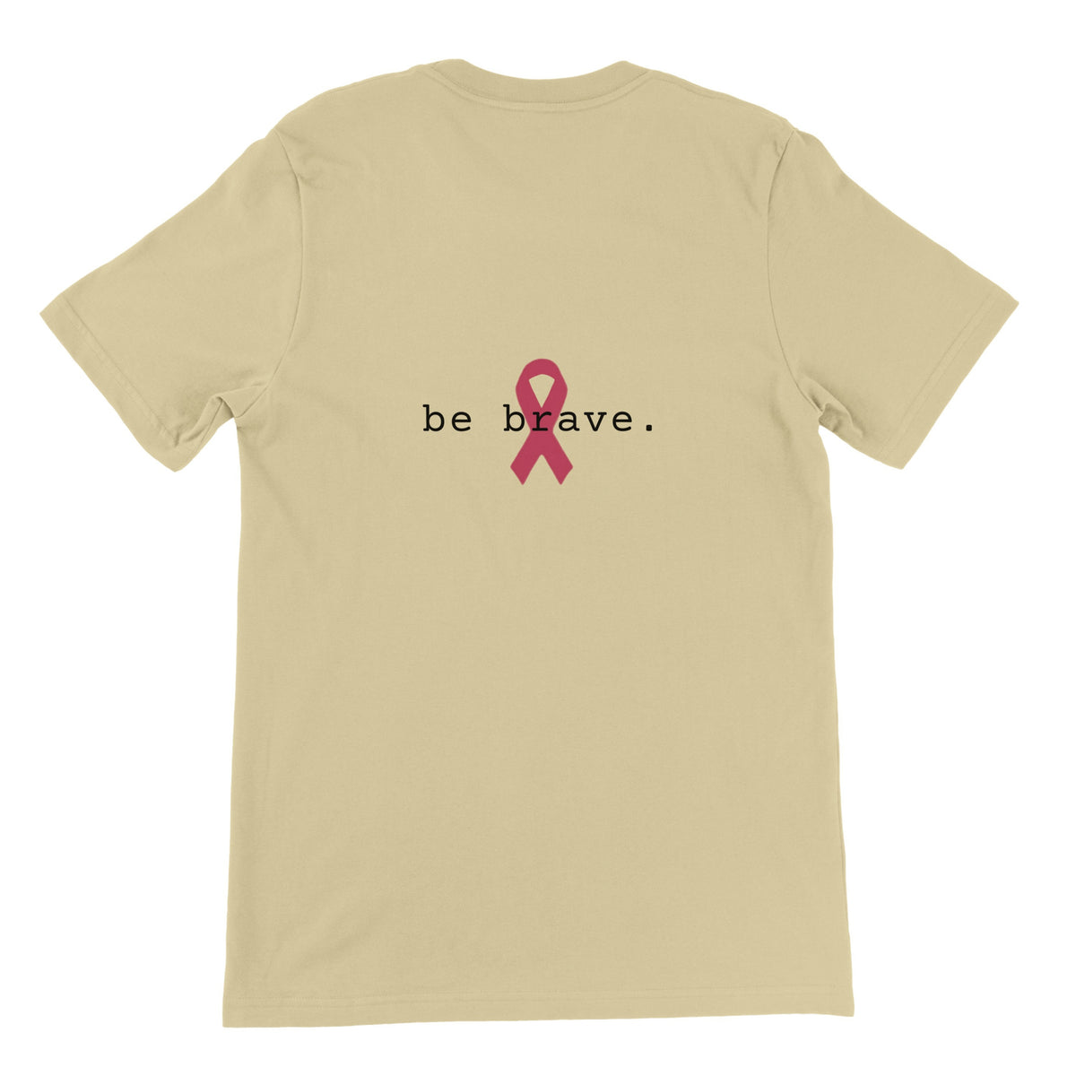 A natural-colored short-sleeve t-shirt is shown from the back, featuring the text 'be brave.' in black with a pink awareness ribbon graphic in the center.