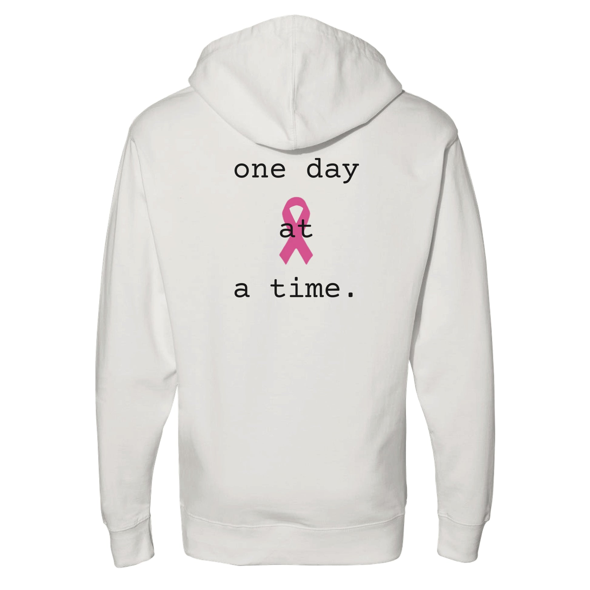 A bone pullover hoodie shown from the back, featuring the printed text 'one day at a time.' in black around a pink awareness ribbon graphic in the center.